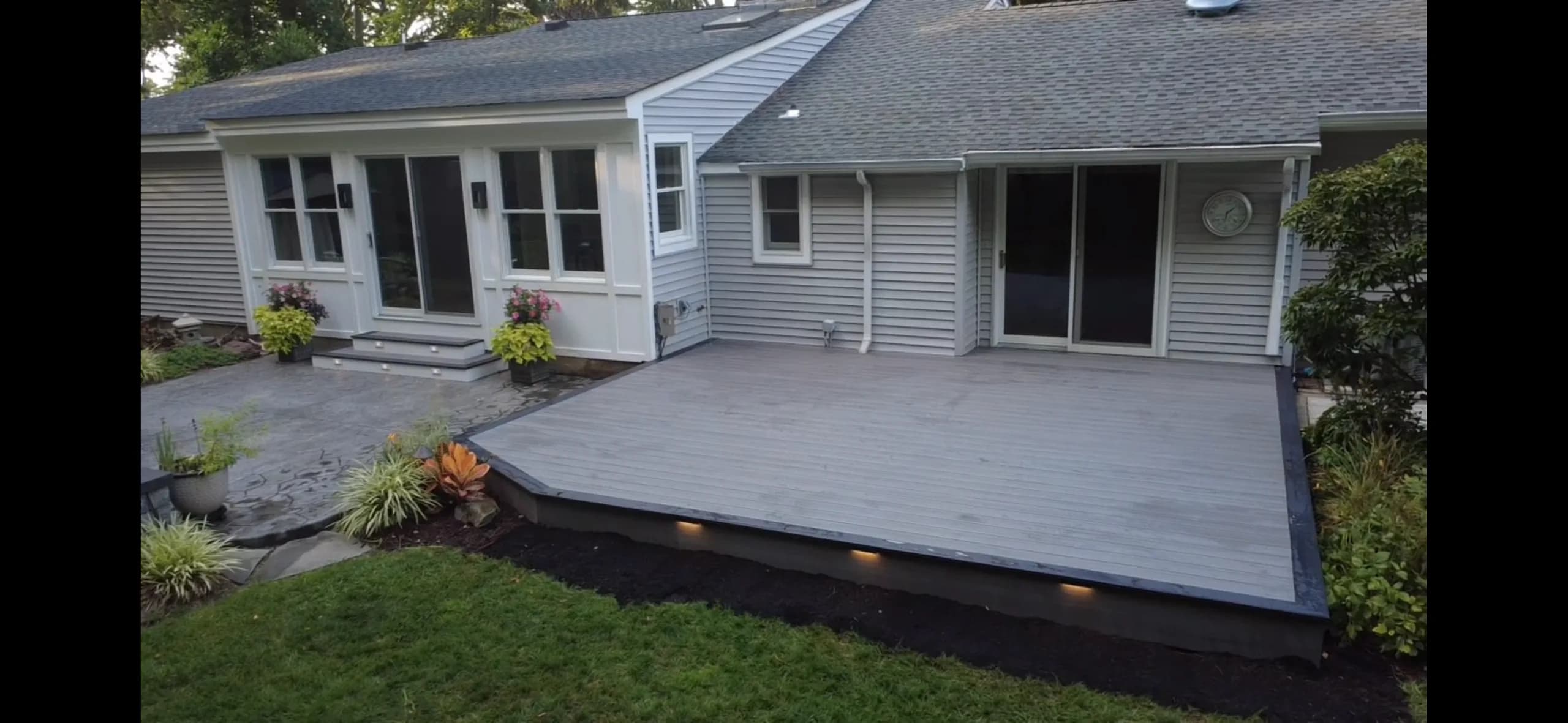 Wide gray composite backyard deck with integrated lighting