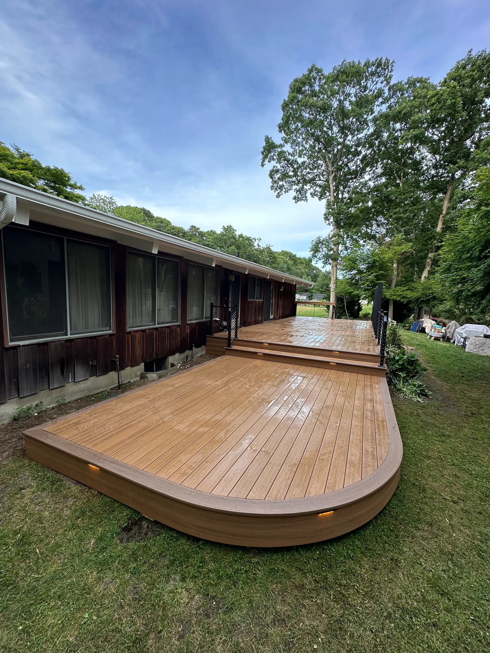 Curved composite deck with integrated lighting in a wooded backyard